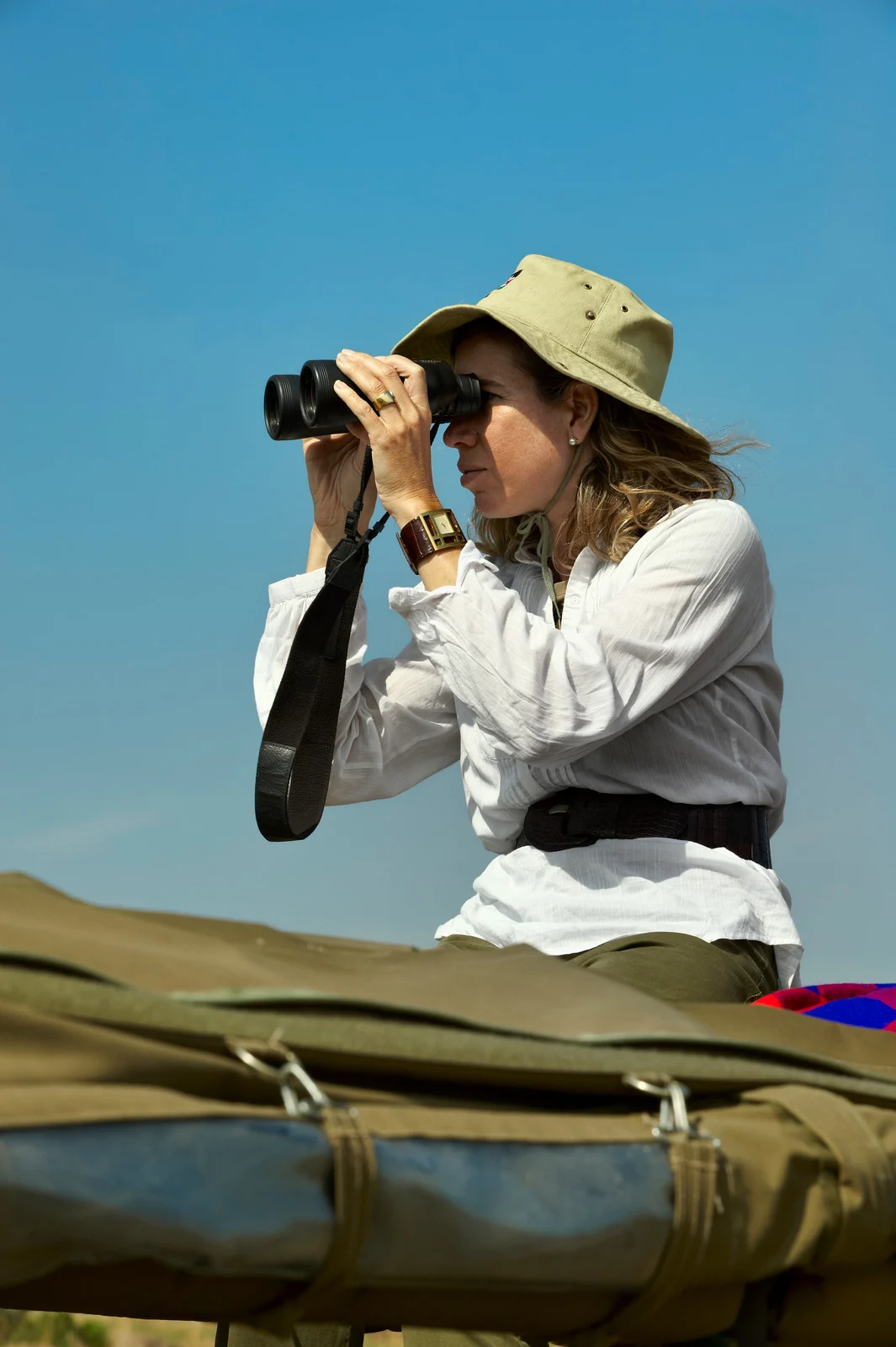 Viaggiatrice con cappello da safari osserva la savana con il binocolo